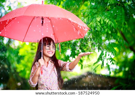 Little asian girl with umbrella in the rain