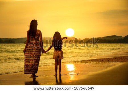 Rear view of a mother and daughter standing on the beach
