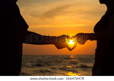 Heart hand of couple on the beach at sunset
