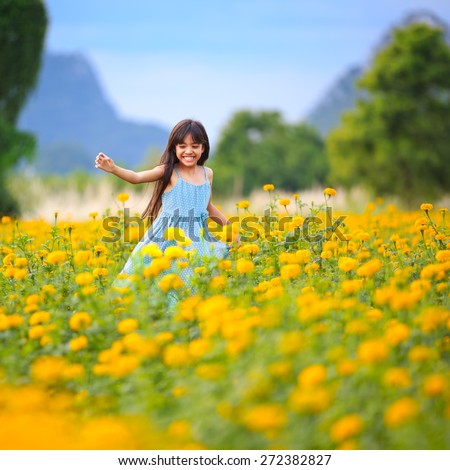Happy little asian girl running on the marigold field