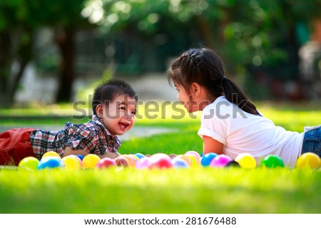 Two children, big syster and her young brother are laying on green