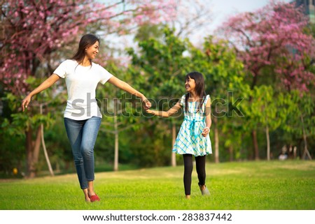 Happy family mother and her daughter running and playing at park