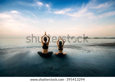 Mother and daughter doing yoga at beach