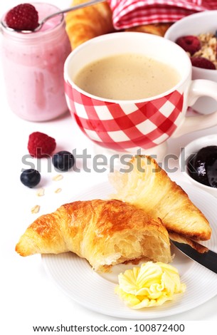 Delicious croissant with butter, jam, coffee and yogurt