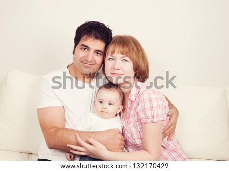 Happy family of free smiling and hugging. Father, mother and son sitting on the sofa, studio shot