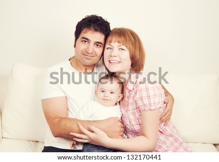 Happy family of free smiling and hugging. Father, mother and son sitting on the sofa, studio shot