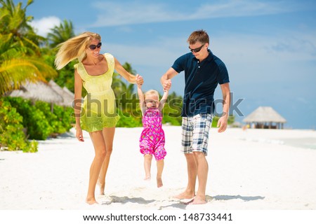 Happy family having fun on the white sandy beach at Maldives