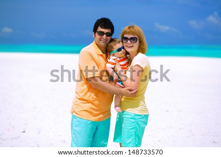 Happy family of three with sun glasses standing on the beach