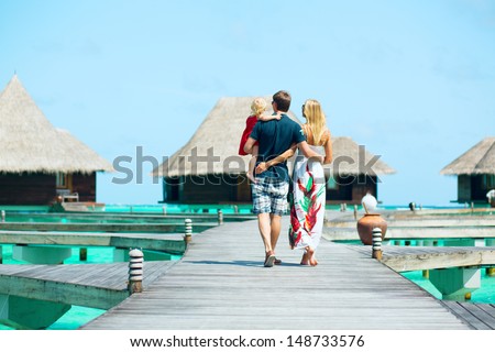 Family from back view having tropical vacation at Maldives, walking towards water bungalows