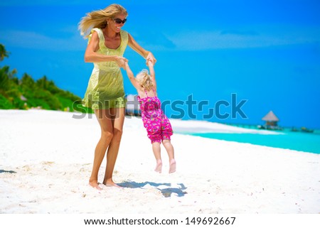 Mother and daughter playing on the white sandy beach at Maldives