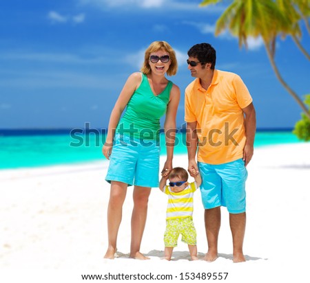 Happy family of three with colorful outfit and sunglasses having tropical vacation on Maldives