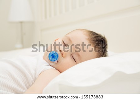 Adorable sleeping baby on the pillow with pacifier, close up indoors shot