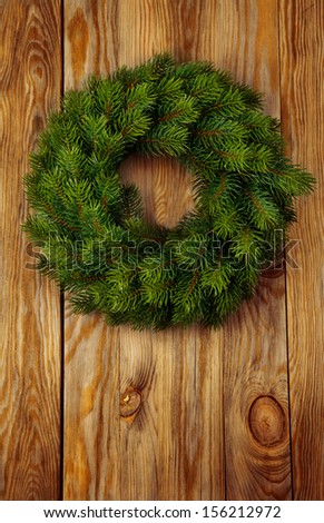 Christmas green wreath from firs brunches without decoration on wooden background with copy space.