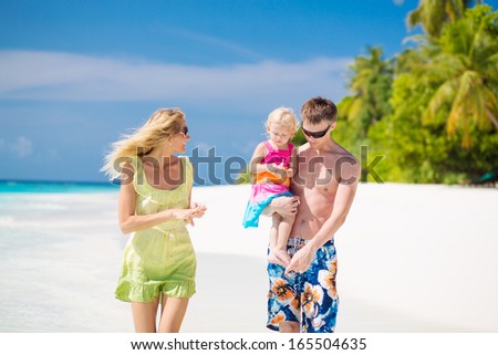 Family of three having tropical vacation on Maldives, walking on the white sandy beach
