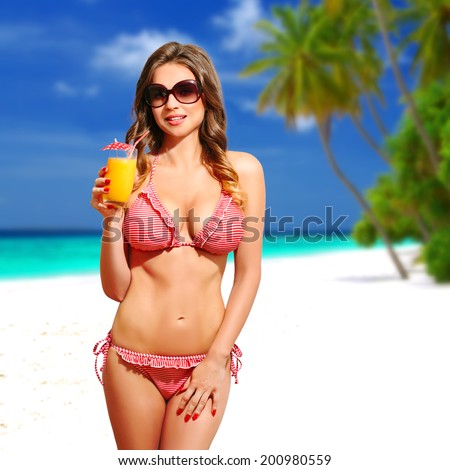 Beautiful sensual woman with bikini, sunglasses and cocktail, on the white sandy beach, Maldives. Half body portrait, long curly blond hair, fashion portrait