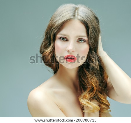 Beautiful woman with professional hair style and make up. Blond curly hair with ombre coloring, clean shiny skin.