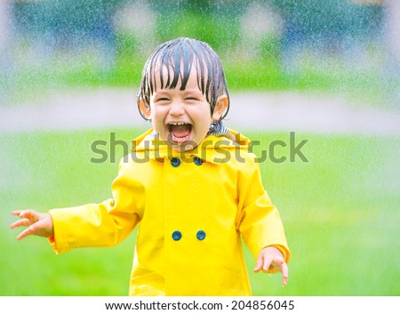 Cheerful, excited baby having fun, running wet under rain, summertime