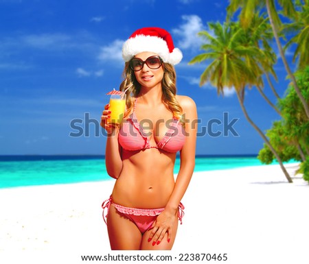 Bikini, fitness model with Santa Hat, sunglasses and cocktail having tropical vacation on Maldives. Happy beautiful woman with suntan, smiling. Christmas card.