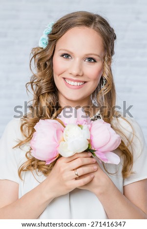 Woman with day bridal make-up and hairstyle, holding bouquet of peonies
