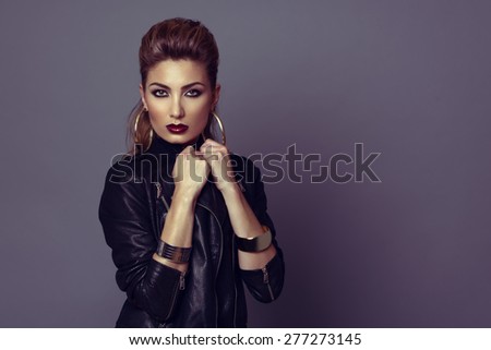Fashion model with rock style hairstyle and make-up, posing with leather jacket.