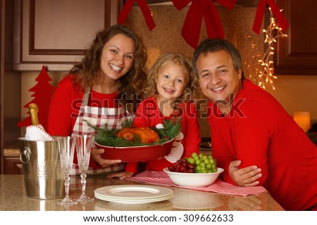 Christmas Holiday Family portrait. Happy family of three preparing Thanksgiving dinner, with turkey and champagne at home. New Year Eve.