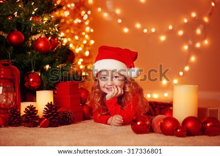 Adorable little girl with Santa Hat, gifts and decorated illuminated Christmas Tree. Greeting card or cover, with copy space