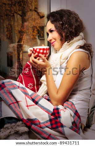 woman with cup of coffee or tea watching out of window