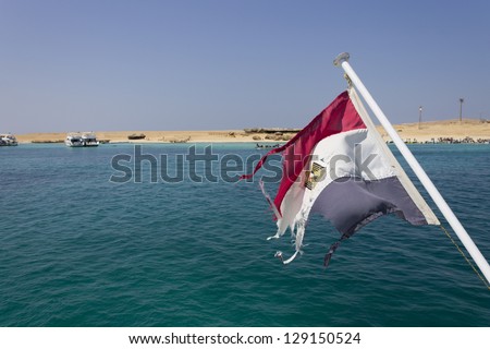 Sea surrounding Hurghada with a beach island in the background and an egyptian flag