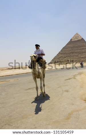 CAIRO, EGYPT - CIRCA JULY 2012 - Policeman on a camel with the Pyramid of Khafre behind him in circa July 2012 in Cairo, Giza. Giza pyramids are one of the most popular monuments among all tourists.