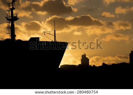 Beautiful golden sunset behind a silhouette of a big cargo ship in Istanbul on Bosporus river and with the Istanbul city in the background