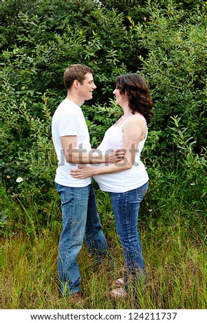 Maternity photos of a couple with brink wall as a background - 8 months pregnant