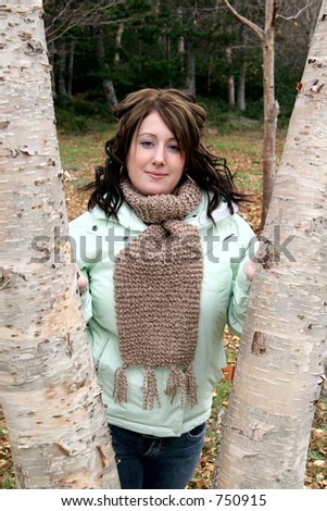 Young woman outdoors in the fall posing between two trees