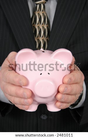 Business man holding Piggy Bank in front of him taken closeup 