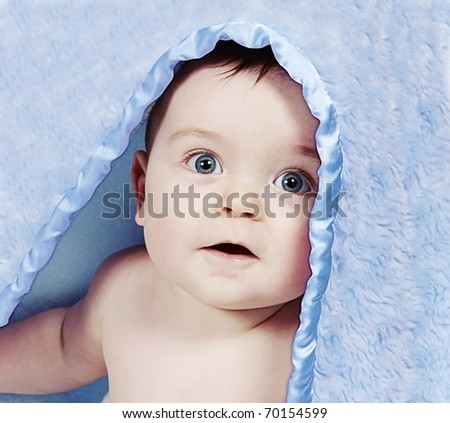 baby boy looking out from under blanket