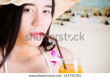 Asian woman on beach drinking cocktail