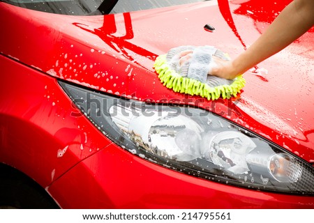 Close-up Of Hand With green Brush Washing Red Car