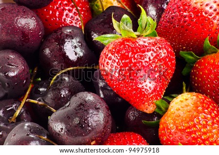 well formed strawberry with leaves in group of strawberries and cheries