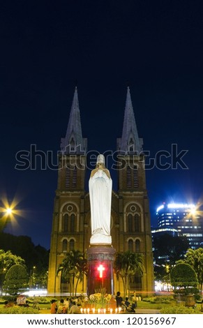 night view of notre dame of Saigon city with people praying by the statue