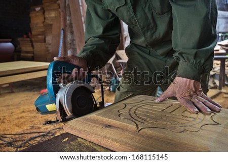 man cutting wood by machine