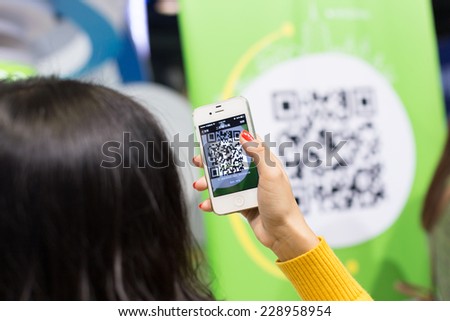 Hangzhou,China-1,11,2014:chines young woman scan the QR code with smart phone.