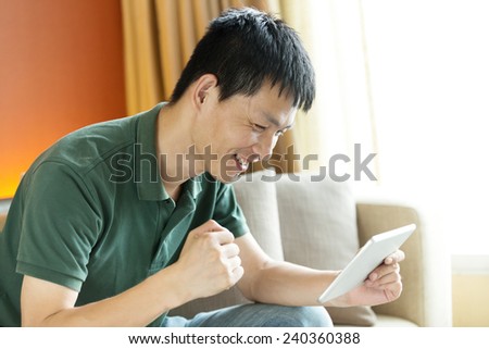 Asian young adult man using tablet and relax on sofa.