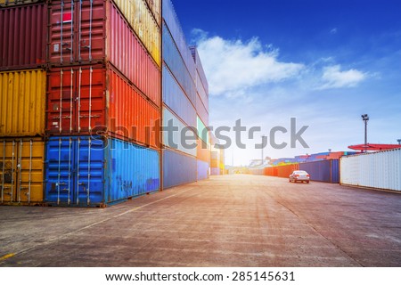 Empty road and containers in harbor at sunset