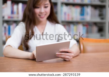 Beautiful asian female student using digital tablet in library