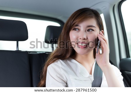 Beautiful asian young woman making phone call in car as passenger