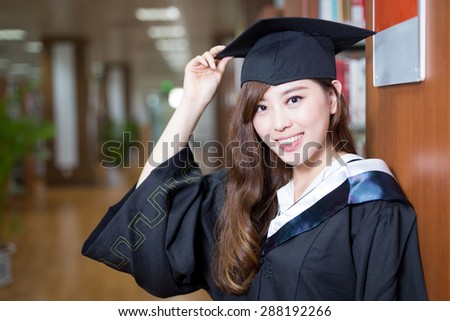 asian beautiful female student wearing academic dress in library portrait
