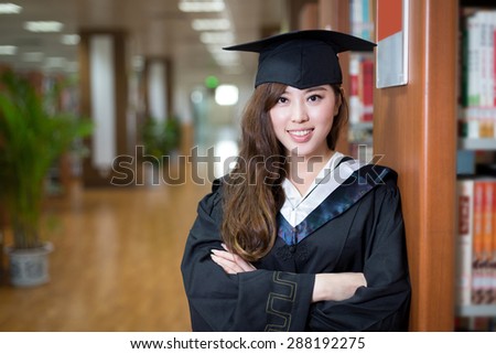 asian beautiful female student wearing academic dress in library portrait