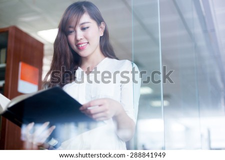Asian beautiful female student holding book in library