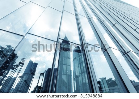 a skyscraper with glass walls and the reflection of landmarks on the opposite side