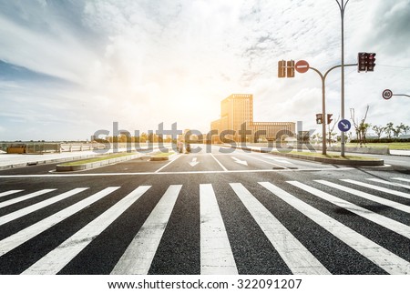empty road with zebra crossing and direction board in modern city under sunlight