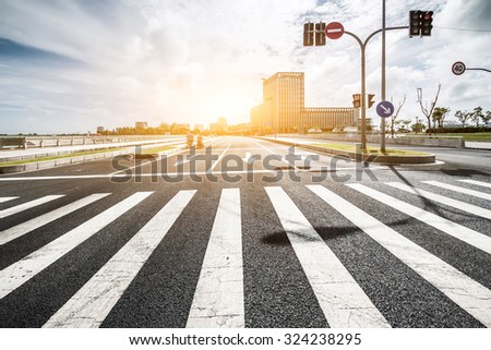 empty road with zebra crossing and direction board in modern city under sunlight